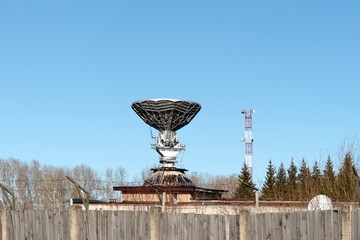 Mirror satellite dish of the Orbita ground-based transceiver station against a blue sky in autumn.