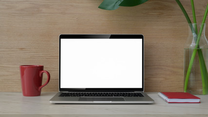 Close up view of workplace with mock up laptop, notebook, coffee cup and decoration on marble desk