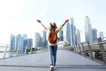 Young Woman Traveler With Backpack And Hat Traveling Into Singapore City Downtown. Travelling In Singapore Concept.
