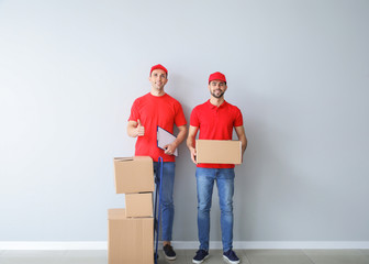 Wall Mural - Delivery men with boxes near light wall