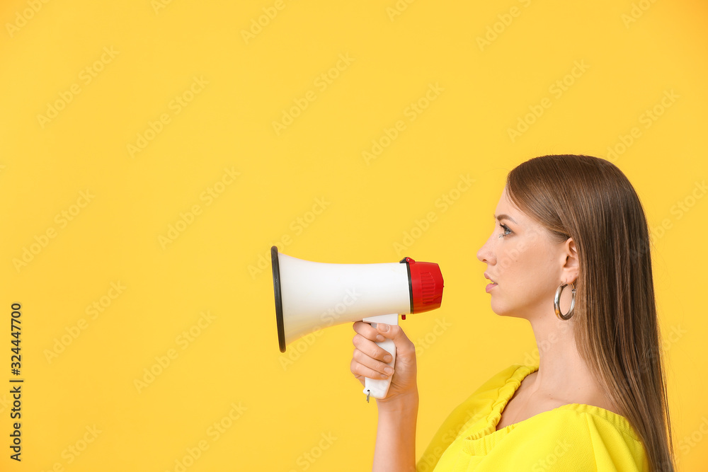 Young woman with megaphone on color background