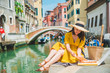 woman sitting on pond with view of venice canal eating pizza