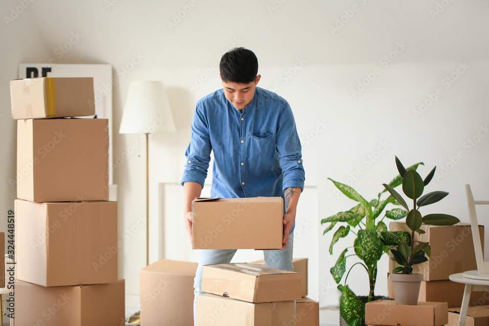 Asian man with belongings at home on moving day