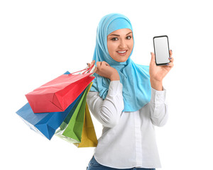 Poster - Young Arab woman with shopping bags and mobile phone on white background