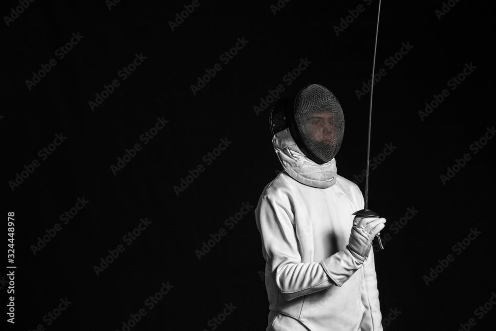 Young fencer on dark  background