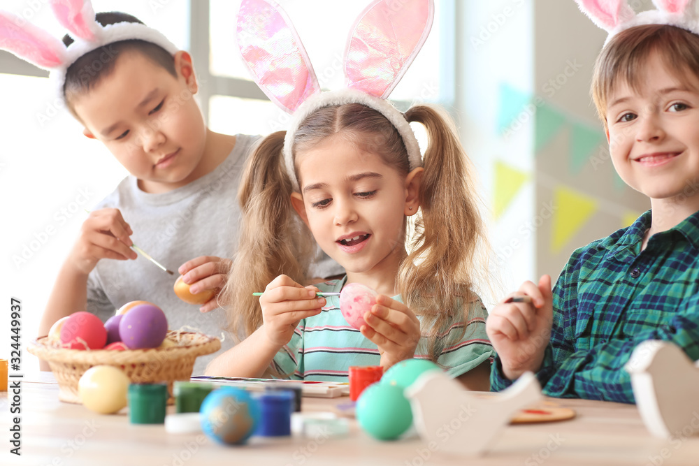 Little children painting Easter eggs at home