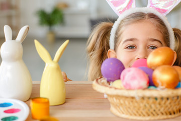 Little girl with painted Easter eggs at home