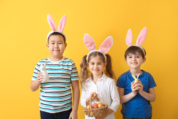 Poster - Little children with Easter eggs and bunny ears on color background