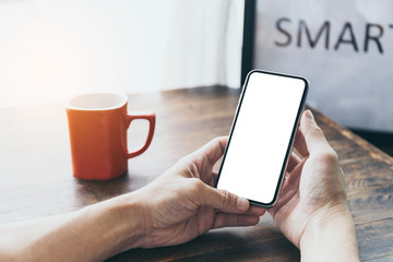 Mockup image blank white screen cell phone.man hand holding texting using mobile on desk at coffee shop.background empty space for advertise text.people contact marketing business,technology