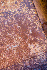 two sheets of rusty metal welded together lie on each other.