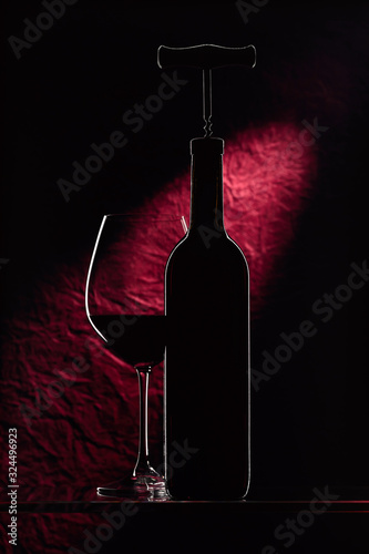 Fotografía Bottle with corkscrew and glass of red wine.