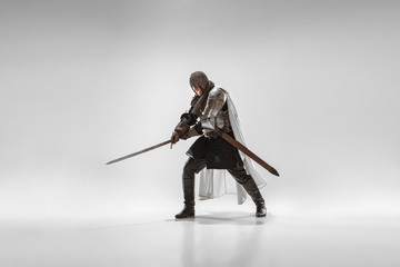 Wall Mural - Brave armored knight with professional weapon fighting isolated on white studio background. Historical reconstruction of native fight of warriors. Concept of history, hobby, antique military art.