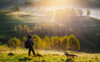 © belyaaa - Photographer and her dog taking pictures of beautiful misty and foggy morning in golden hour on a peaceful meadow.