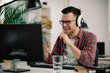 © JustLife - Attractive businessman in office. Young programmer with headphones singing at work.