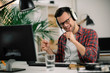 © JustLife - Attractive businessman in office. Young programmer with headphones singing at work.