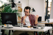 © JustLife - Attractive businessman in office. Young programmer with headphones singing at work.