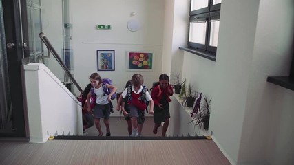 Wall Mural - Group of cheerful small school kids running up the stairs.