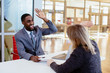 © Carlos David - Portrait of a happy smiling young man in business suit celebrating while giving a high five to woman coworker or client in meeting