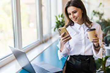 Attractive business woman drinking coffee in her office. Pretty young business woman having coffee at her workplace. Female coworker at modern workspace drinking coffee.