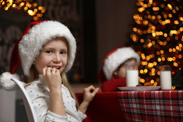 Poster - Cute little children eating cookies at table in dining room. Christmas time