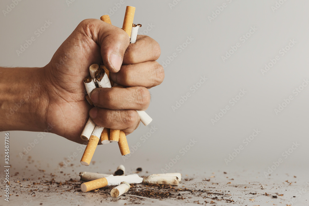 Photo Stock Hand clutching cigarette and crush for destroy.Cigarettes is  addictive to be cancer.smoking reduction campaign in World No Tobacco Day. 