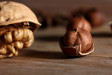 Sticker - hazelnuts and walnuts with split shells on a wooden table close-up