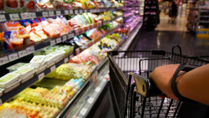 Man pushing shopping cart of food in the supermarket,a man in the purchase of food in a supermarket. everyday life of a husband.