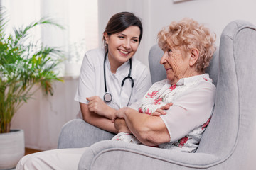 Canvas Print - Senior seating on armchair in nursing home and talking to doctor