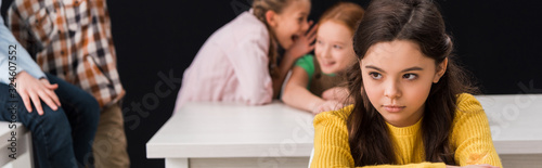 Fotomural panoramic shot of upset schoolkid near classmates gossiping and laughing isolate