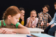© LIGHTFIELD STUDIOS - selective focus of classmates laughing and pointing with fingers at schoolgirl isolated on black, bullying concept
