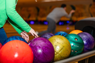  Child's hands reaching to pick up bowling ball at Bowling alley