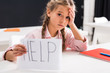 © LIGHTFIELD STUDIOS - selective focus of sad schoolgirl holding paper with help lettering, bullying concept