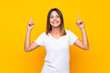 © luismolinero - Young woman over isolated yellow background pointing up a great idea