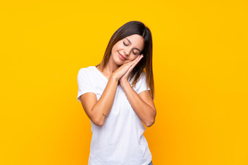 Young woman over isolated yellow background making sleep gesture in dorable expression