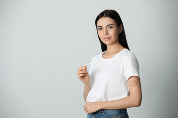 young woman with nicotine patch and cigarette on light grey background. space for text