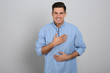 Handsome grateful man with hands on chest against light grey background