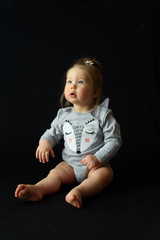 Wall Mural - little girl sitting on a black background