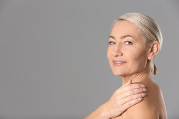 Poster - Portrait of beautiful mature woman on grey background. Space for text