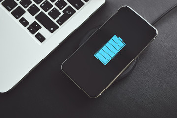 Wall Mural - top view of mobile phone while charging wirelessly next to laptop
