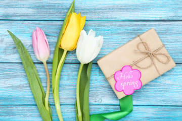 Wall Mural - Tulip flowers with text Hello Spring and gift box on blue wooden table