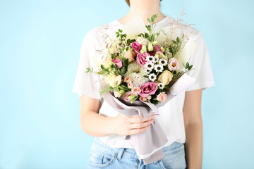 Wall Mural - Female hand holding beautiful flower bouquet on blue background