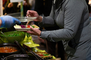 Hands of a person with a ready to eat food box or tasting in a brown cardboard box at a street food market. Brick Lane, London