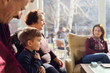 © Miljan Živković - Portrait of small Caucasian boy three years old child sitting by his grandmother grandfather and mother family at home or restaurant in sunny day holding his shirt looking away side view
