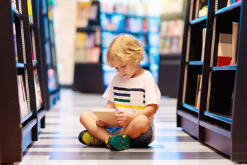 Child in school library. Kids reading books.