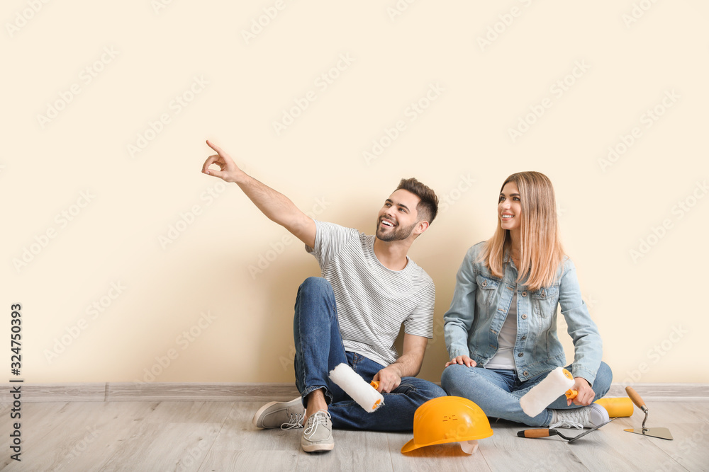Young couple with tools resting during repair in new apartment