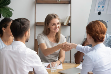 Wall Mural - Smiling businesswoman shaking hand of business partner at meeting