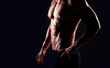 © Acronym - Strong, fit and sporty bodybuilder man over black background.