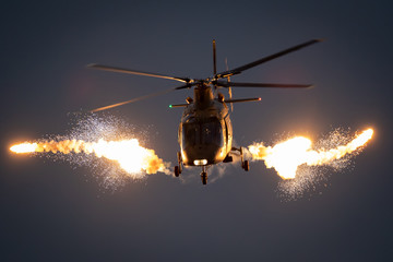 Wall Mural - Military helicopter in flight firing off flare decoys at night.