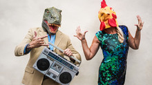 Crazy Senior Couple Dancing At Carnival Party Wearing T-rex And Chicken Mask - Old Trendy People Having Fun Listening Music With Boombox Stereo - Absurd And Funny Trend Concept - Focus On Faces