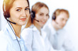 © rogerphoto - Call center operators. Focus on beautiful business woman using headset in sunny office